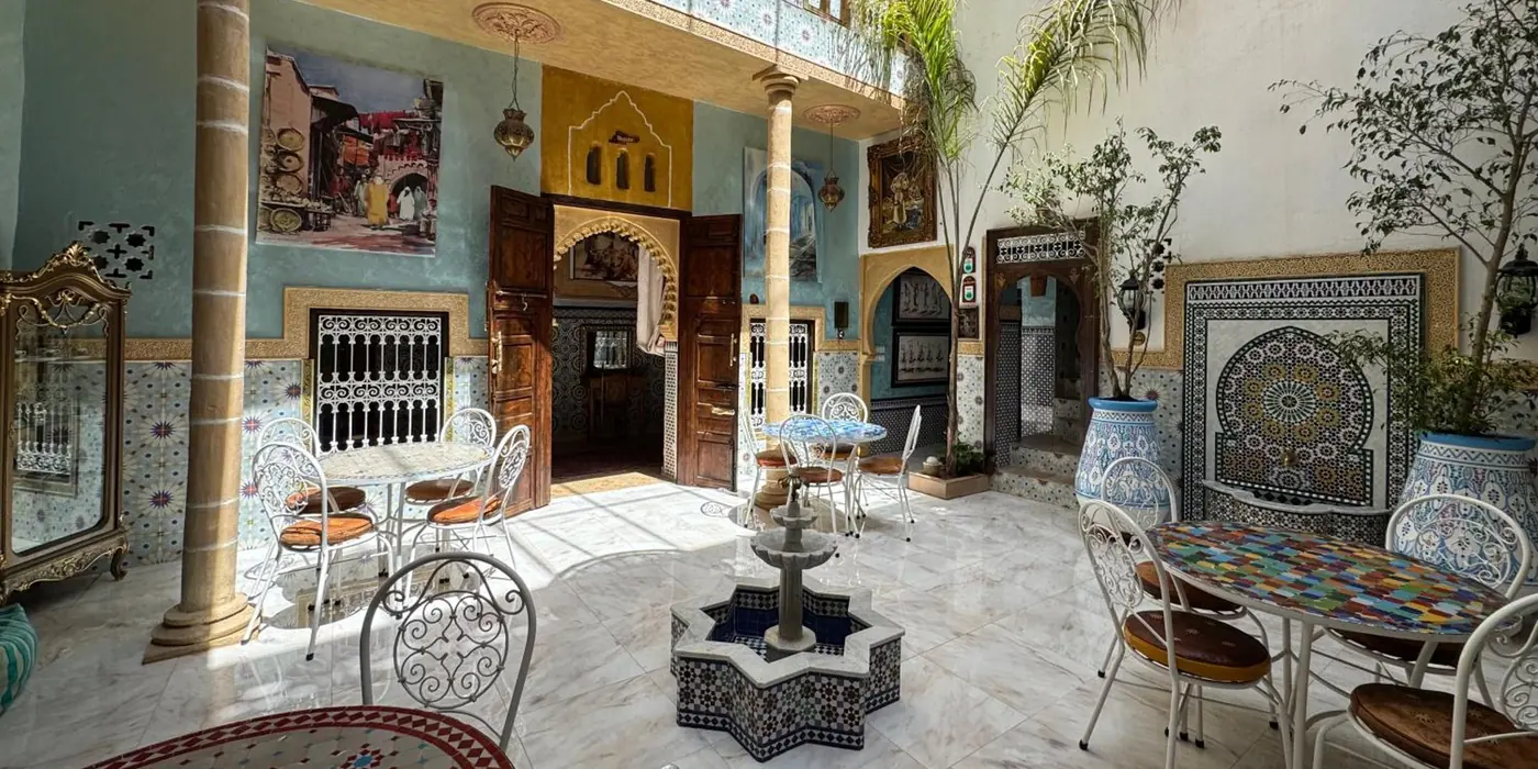 Le patio de jour, la fontaine en étoile et les tables en zellige