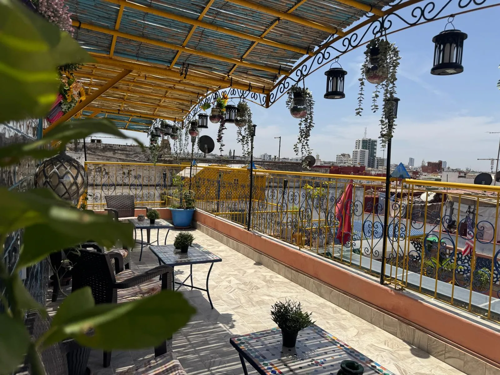 Le rooftop sous la pergola, les lanternes et la vue sur la ville
