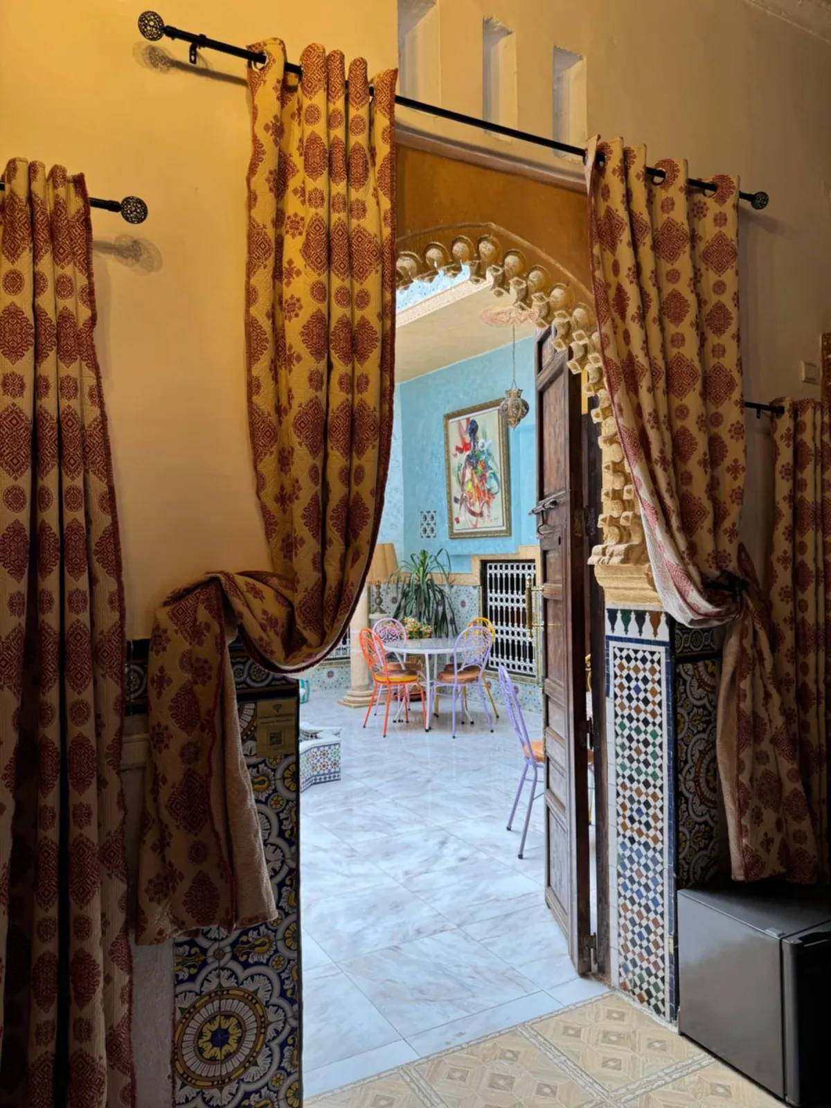Une porte sous un arc sculpté, rideaux tirés sur le patio
