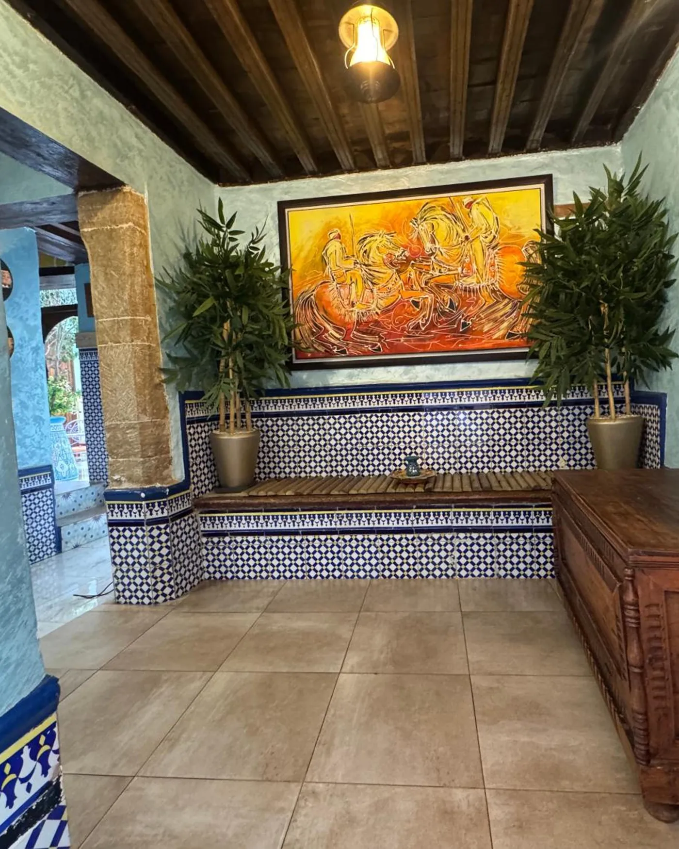 Un coin du patio, mur bleu, banquette et grande toile